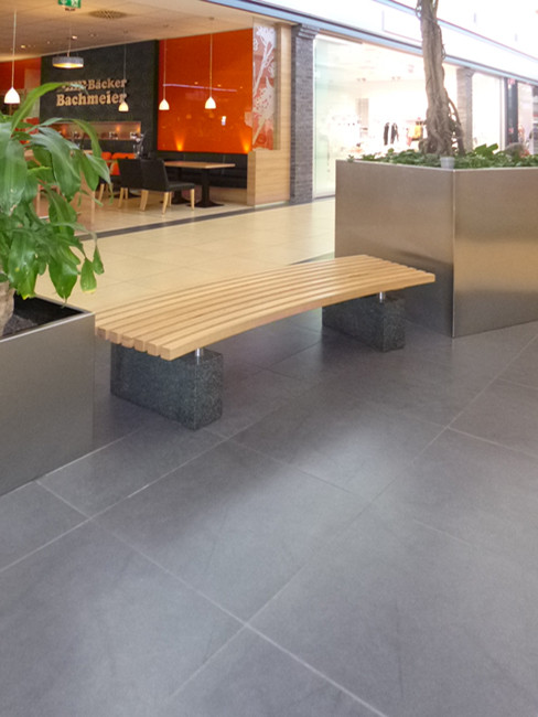 LARCO Sitzbank mit Buchenholzleisten im Radius geschnitten und Granitfuß sowie Edelstahlpflanzgefäßen von sixnine-design